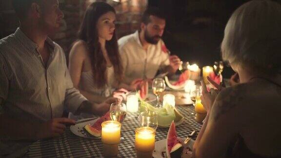 在夏日的夜晚无忧无虑的白种人朋友享受着晚宴上随意的交谈