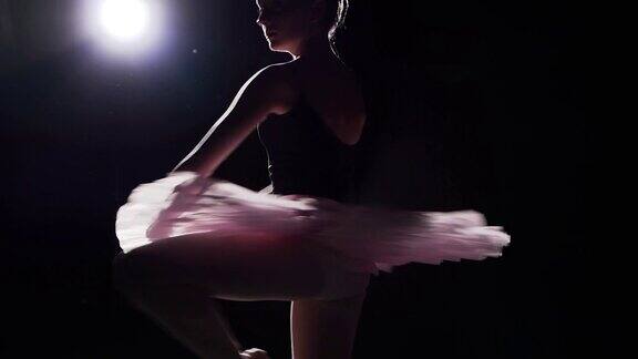 芭蕾舞演员在演播室跳舞的慢动作镜头黑色背景上的美丽女芭蕾舞者穿着芭蕾舞短裙和尖头鞋的芭蕾舞女演员缓慢的运动