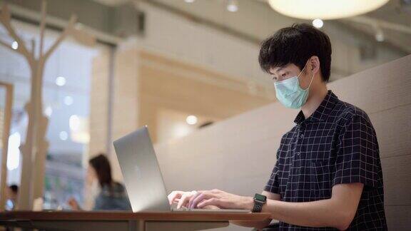 亚洲人戴着卫生口罩工作时保持社交距离