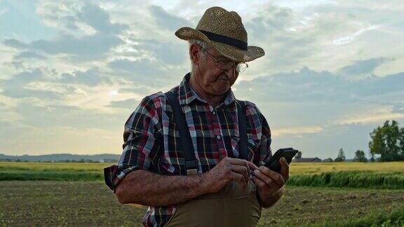 在田里工作时使用智能手机的资深农民