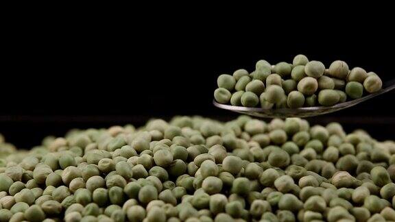 绿色豌豆掉落孤立的黑色背景与滑动相机拍摄