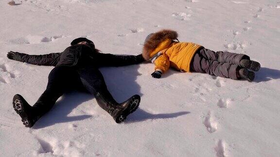 一家人躺在雪地里堆着雪天使母亲和孩子躺在雪地上