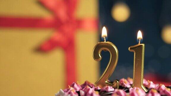 21号生日蛋糕用金色蜡烛点燃蓝色背景的礼物用黄色礼盒系上红丝带特写和慢动作