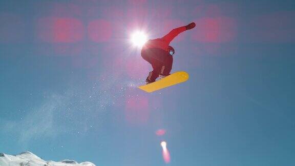 慢动作:专业滑雪板运动员在冬季滑雪场的太阳上跳跃和飞行