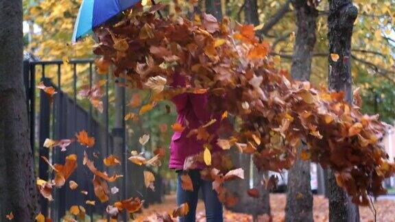 小女孩在公园里玩秋天的落叶孩子笑着扬起金黄色的枫叶