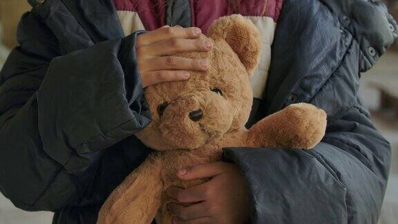 肮脏女孩的手拿着泰迪熊的特写