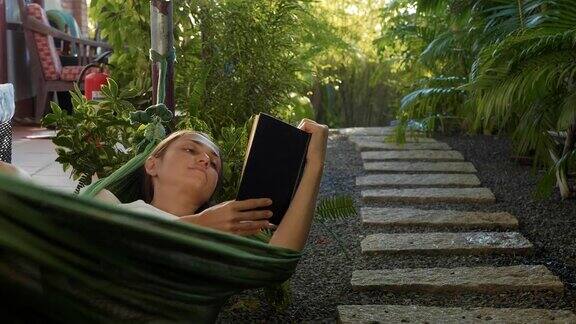 年轻女子躺在阳台上的吊床上看书