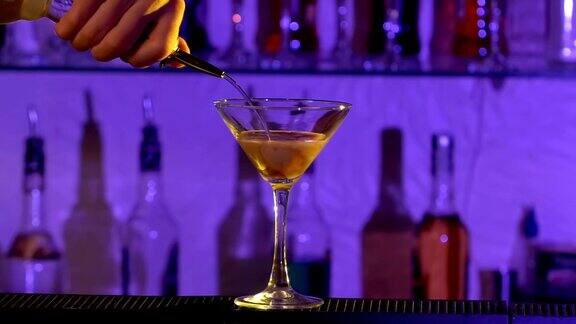 酒保倒一种利口酒和混合两种不同的酒精液体鸡尾酒杯在酒吧慢动作