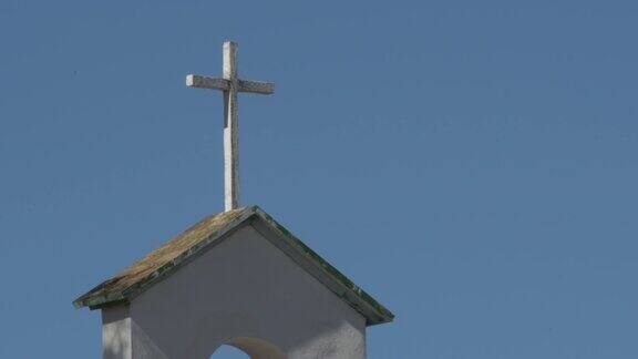 古老的十字架在一个村庄教堂的白色钟楼在安达卢西亚