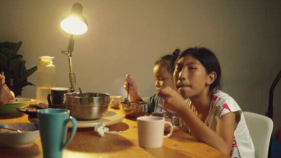 快乐亚洲男孩女孩晚上在家一起吃饭生活理念
