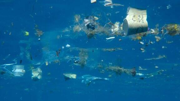 慢镜头巨大的塑料和其他碎片在阳光下慢慢漂浮在蓝色的海洋表面下塑料垃圾环境污染问题红海的塑料污染