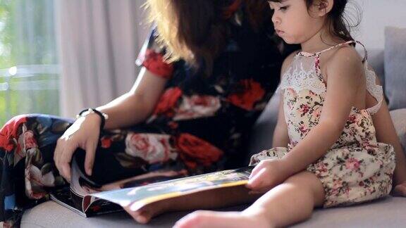 年轻的妈妈给她的小女儿读书