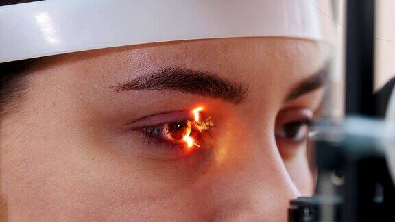 眼科治疗-一个年轻的女人用一个特殊的大验光机检查她的视力-棕色的眼睛颜色