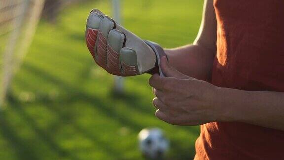 年轻的足球守门员戴着手套站在足球场