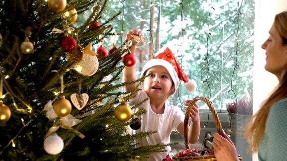 可爱的小女孩和妈妈一起装饰圣诞树