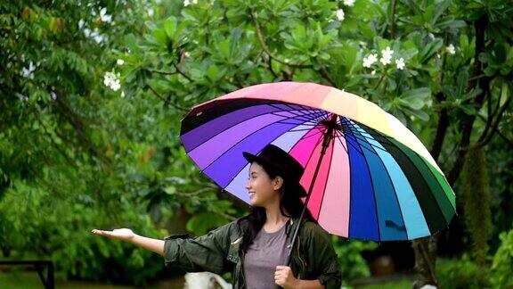 亚洲女人从五颜六色的伞上玩雨滴