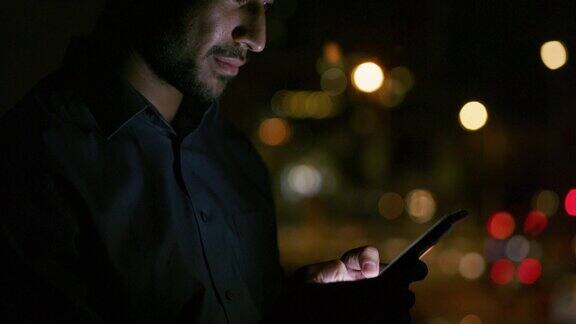 一个英俊的年轻商人晚上站在办公室外用手机的4k视频片段