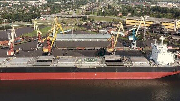 拉脱维亚VENTSPILS-2019年7月:将货物装载到干货船和铁路车厢的港口起重机鸟瞰图