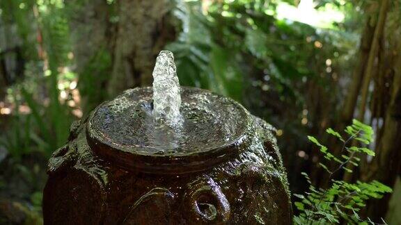 慢镜头水缸喷泉在绿色花园