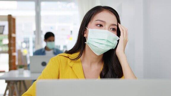 亚洲自由职业女性戴着口罩使用笔记本电脑在新的正常家庭办公室努力工作