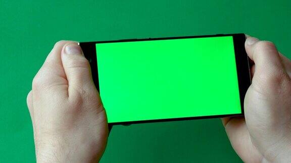 玩家在智能手机上玩游戏屏幕上显示拷贝空间触屏手指按在智能手机的绿色屏幕上显示带有色度键的智能手机