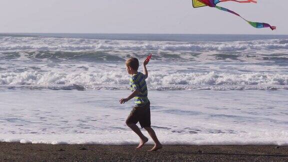 小男孩拿着风筝在海滩上奔跑慢镜头