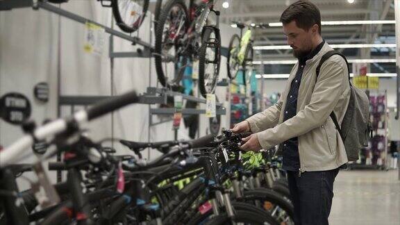 一名蓄着胡须的成年男子正在一家运动器材店检查自行车