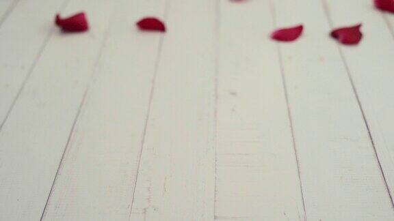 用红玫瑰花瓣制成的心分散在白色木桌上