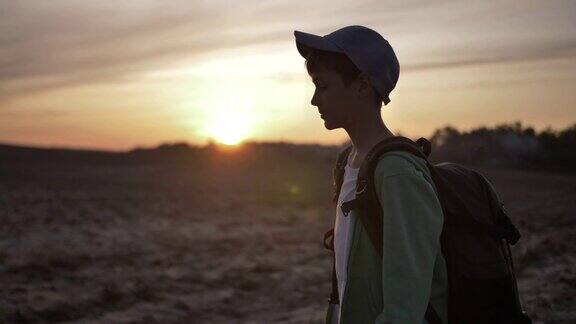 背着背包的小男孩在日落时分在户外散步