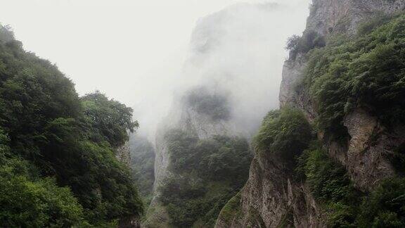 俄罗斯高加索地区覆盖着植被和云层的陡峭的岩石山脉