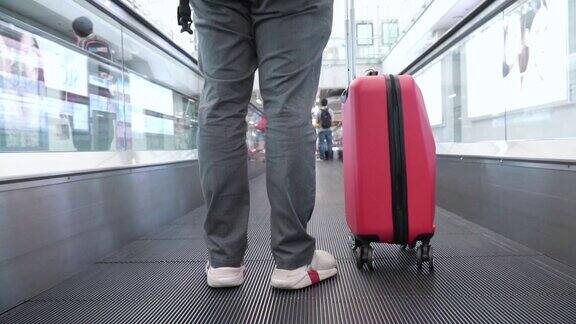 在机场的自动扶梯上拿着旅行袋的男人