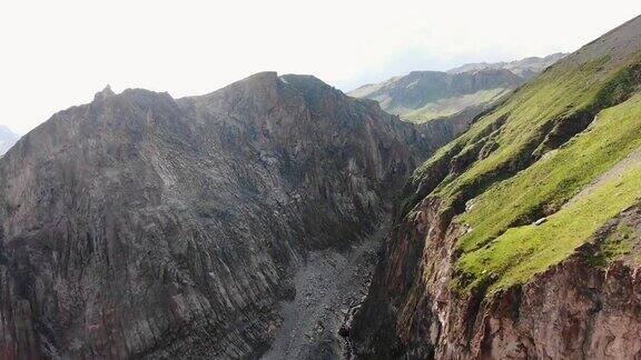 巨大的棕色陡峭的悬崖顶上长满了草峡谷里有河流