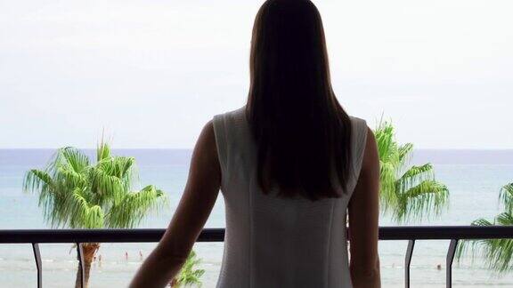 女士打开阳台滑动玻璃门从阳台上欣赏地中海海景