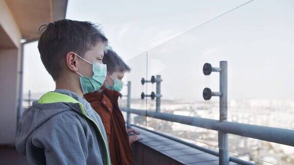 三个孩子戴着防毒面具在阳台上玩