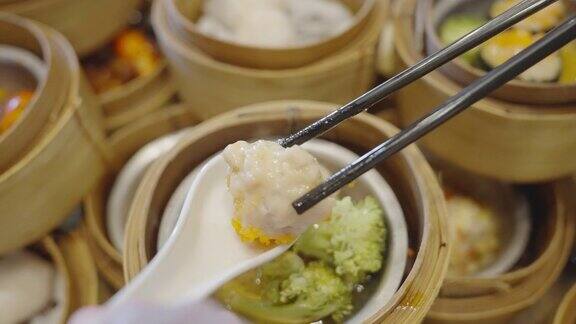 用筷子从竹蒸笼里夹出一块中国饺子