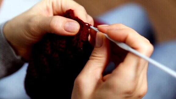 特写女人的手编织红色勃艮第羊毛纱线