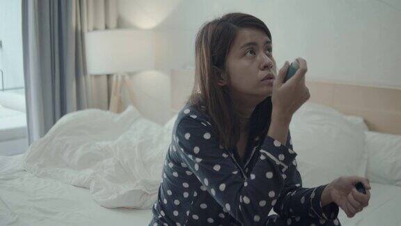 年轻女子在家里的床上使用哮喘吸入器