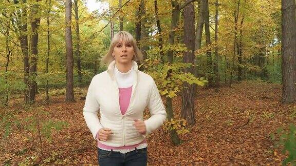 高清稳定镜头:年轻女子在秋天的森林里慢跑