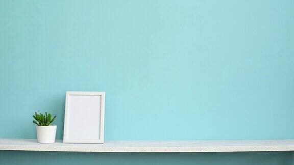 现代房间装饰与画框模型白色的架子对着淡蓝色的墙壁用手放下多肉植物盆栽