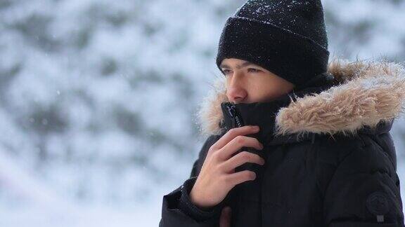 肖像年轻的冻结男孩站在森林地区在寒冷的一天大雪旋风