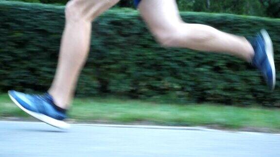 夏日里在人行道上奔跑的运动男子的脚年轻运动员的双腿在自然的道路上快速奔跑强壮的运动员在户外慢跑健康积极的生活方式低的观点