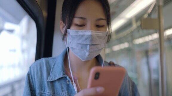亚洲女性在乘坐地铁或火车时会戴口罩、使用智能手机和耳机并保持社交距离
