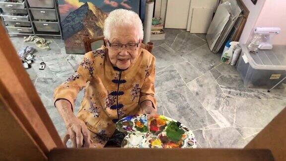 亚洲华人微笑的老年妇女在她的房子的画布上绘画