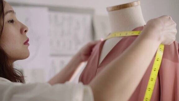 女设计师在时装设计工作室测量她的设计服装