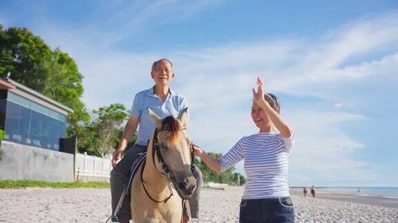 亚洲老年夫妇一起在海滩上骑马成熟的年长的祖父母旅行者在夏天的热带海岛度假旅行时感到快乐和放松