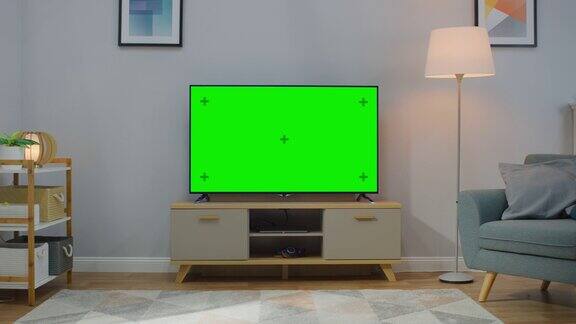 缩小镜头的电视水平绿色屏幕模拟起来舒适的客厅白天与椅子和灯打开在家里