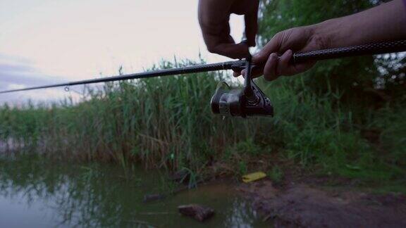 渔夫手持鱼竿在湖面上旋转渔轮