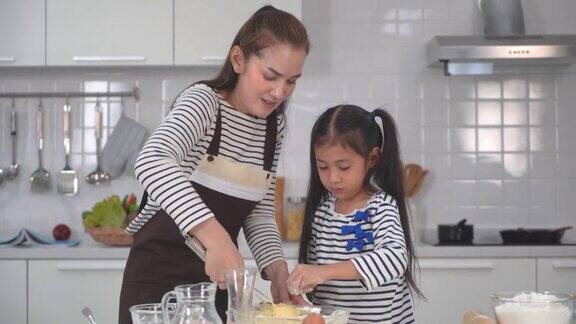 为了家庭活动母亲和女儿在家庭厨房一起做面包面团