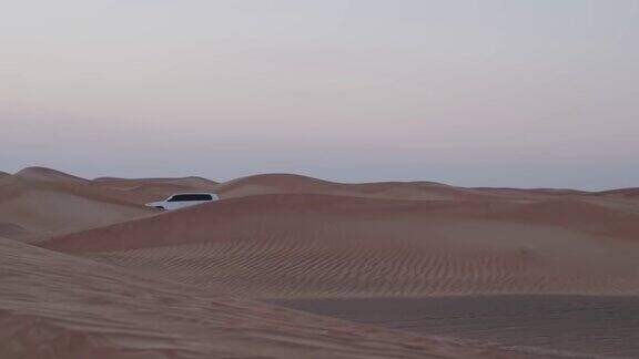 一队白色越野车穿过沙漠的沙丘