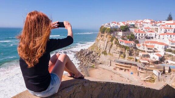女游客在海边的悬崖上拍照